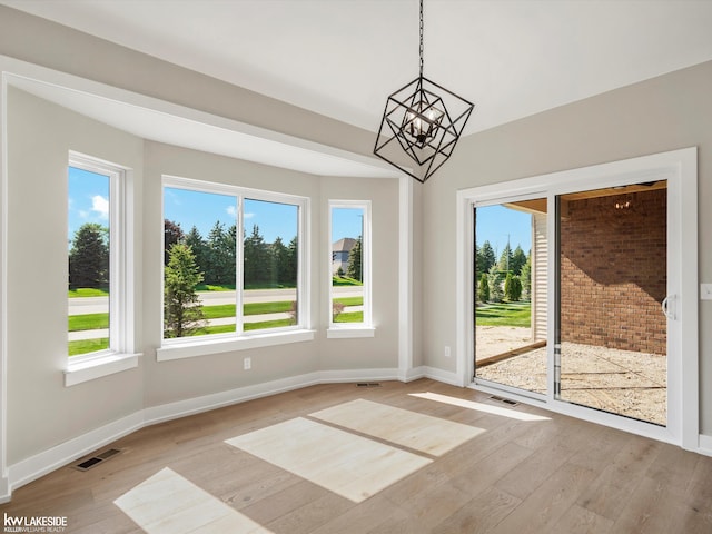 55127 Saint Paul Dr, Macomb Twp, MI 48042 - unfurnished dining area with wood finished floors, a chandelier, and plenty of natural light