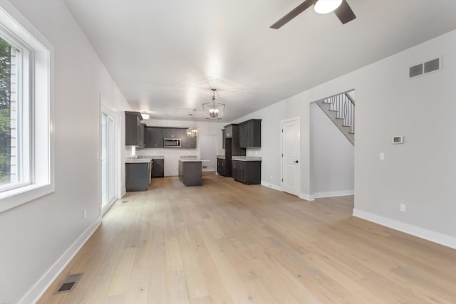 29126 Brooke Meadows Ct, Chesterfield, MI 48047 - unfurnished living room featuring light wood-style floors, ceiling fan, baseboards, and stairs