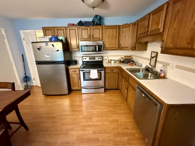 2222 Compton St, Saginaw, MI 48602 - kitchen featuring stainless steel appliances, a sink, light wood-style floors, brown cabinetry, and backsplash