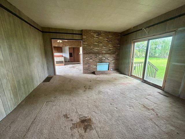 4992 Freeman Rd, Beaverton, MI 48612 - unfurnished living room featuring wooden walls, carpet flooring, and a brick fireplace