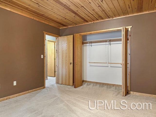 7730 Tipperary Ave, Gladstone, MI 49837 - unfurnished bedroom with carpet, wood ceiling, baseboards, and a closet
