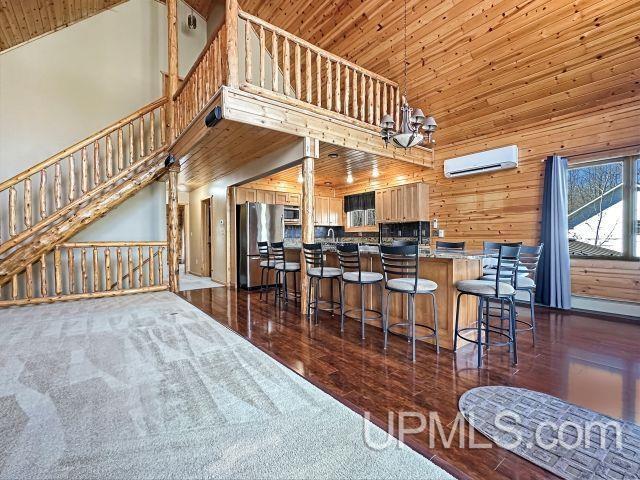 7730 Tipperary Ave, Gladstone, MI 49837 - kitchen featuring appliances with stainless steel finishes, high vaulted ceiling, an AC wall unit, wooden walls, and wooden ceiling