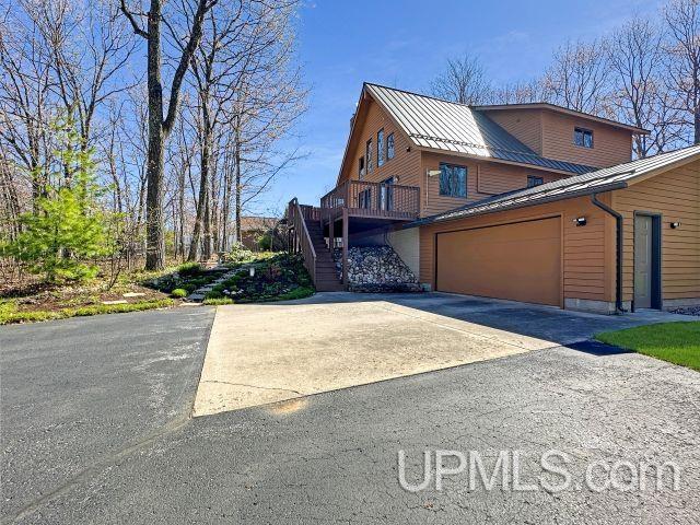 7730 Tipperary Ave, Gladstone, MI 49837 - view of front of home featuring driveway, stairway, metal roof, a standing seam roof, and a garage