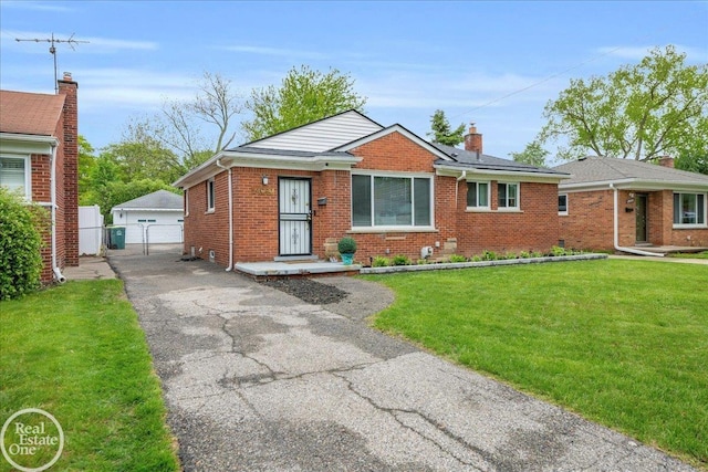 24080 Scotia Rd, Oak Park, MI 48237 - view of front of house featuring brick siding, an outbuilding, a garage, roof mounted solar panels, and a gate