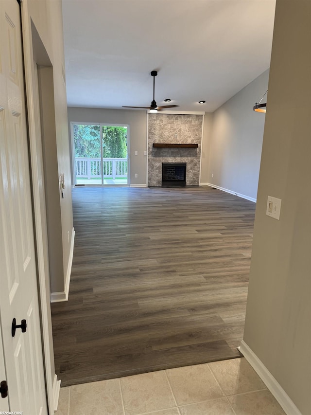 16180 Scenic Dr, Clinton, MI 48038 - unfurnished living room featuring a stone fireplace, ceiling fan, baseboards, and wood finished floors