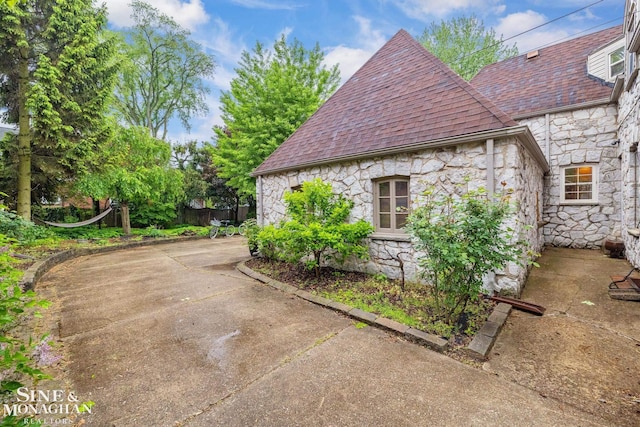 255 Lewiston Rd, Grosse Pointe Farms, MI 48236 - view of home's exterior with stone siding, a patio area, and a shingled roof