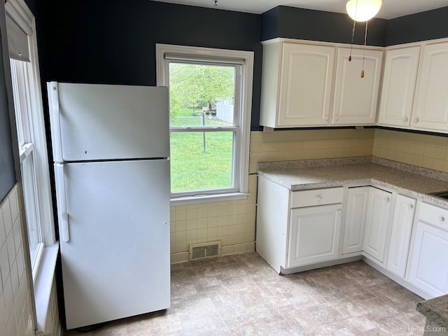 249 E Michigan Ave, Ironwood, MI 49938 - kitchen with freestanding refrigerator, healthy amount of natural light, white cabinetry, and tile walls