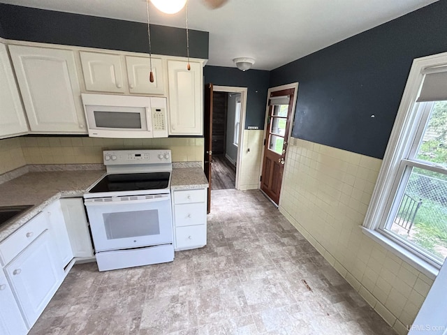 249 E Michigan Ave, Ironwood, MI 49938 - kitchen featuring white appliances, white cabinets, light countertops, tile walls, and a wainscoted wall