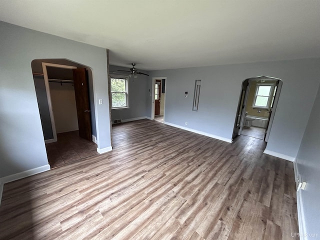 249 E Michigan Ave, Ironwood, MI 49938 - unfurnished living room featuring arched walkways, a ceiling fan, wood finished floors, and baseboards