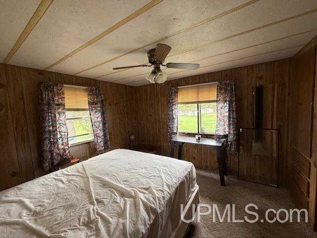 11843 Howen Rd, Long Lake T-Wi, WI 54542 - bedroom with wooden walls, carpet flooring, a textured ceiling, and a ceiling fan