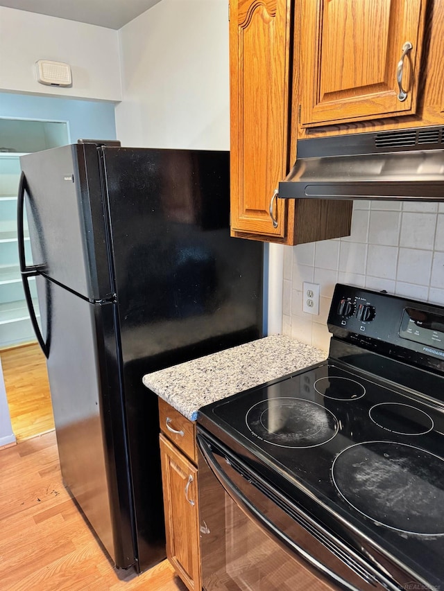 28724 Sutherland Dr, Warren, MI 48088 - kitchen featuring black appliances, under cabinet range hood, light wood finished floors, and brown cabinets