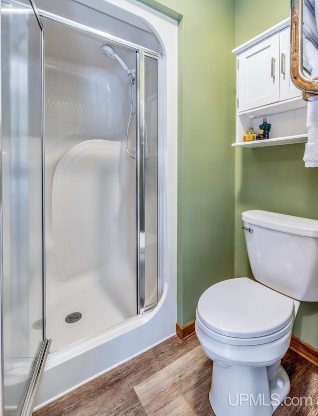 1128 E E St, Iron Mountain, MI 49801 - full bathroom featuring wood finished floors, a stall shower, baseboards, and toilet