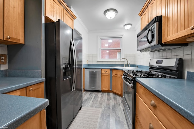 20681 Beaufait St, Harper Woods, MI 48225 - kitchen featuring appliances with stainless steel finishes, a sink, crown molding, light wood-style flooring, and decorative backsplash