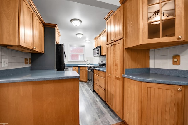 20681 Beaufait St, Harper Woods, MI 48225 - kitchen with appliances with stainless steel finishes, backsplash, dark countertops, wood finished floors, and glass insert cabinets