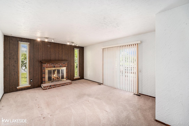 6019 Kingsfield Dr, West Bloomfield, MI 48322 - unfurnished living room with carpet flooring, track lighting, a textured ceiling, wood walls, and a brick fireplace