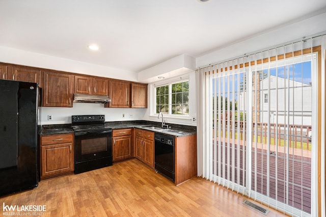 6019 Kingsfield Dr, West Bloomfield, MI 48322 - kitchen featuring black appliances, under cabinet range hood, light wood finished floors, a sink, and dark stone countertops