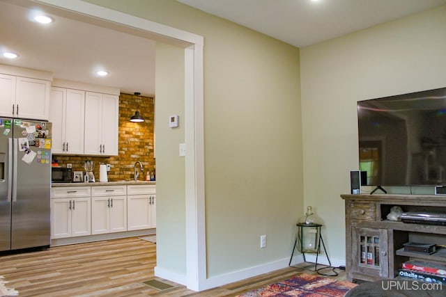 19390 W Calverley St, Houghton, MI 49931 - kitchen featuring stainless steel fridge, light wood-style flooring, black microwave, white cabinets, and recessed lighting