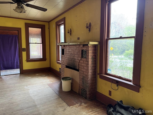2003 Center St, Marquette, MI 49855 - unfurnished living room featuring a ceiling fan, a fireplace, light wood-style flooring, and crown molding