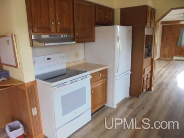 605 W 5th St, Rockland, MI 49960 - kitchen featuring white appliances, under cabinet range hood, light wood-style flooring, light countertops, and brown cabinetry