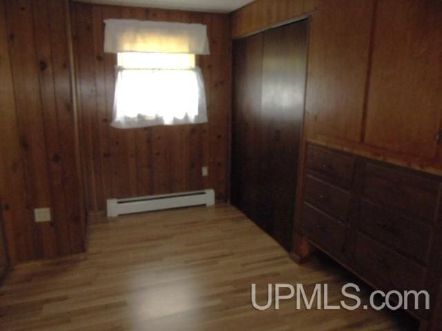 605 W 5th St, Rockland, MI 49960 - corridor featuring a baseboard radiator, light wood-style flooring, and wood walls