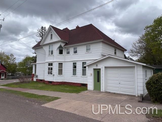708 Calumet St, Lake Linden, MI 49945 - victorian-style house featuring a garage, an outbuilding, concrete driveway, and a chimney