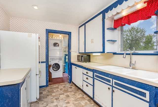 107 State Park Dr, Bay City, MI 48706 - kitchen with stacked washer / drying machine, a sink, white cabinets, light countertops, and wallpapered walls