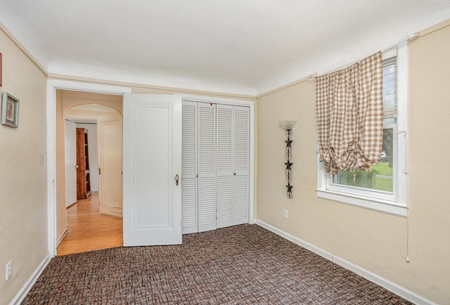 107 State Park Dr, Bay City, MI 48706 - unfurnished bedroom featuring arched walkways, a closet, carpet floors, and baseboards