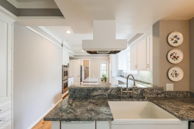 257 Ridge Rd, Grosse Pointe Farms, MI 48236 - kitchen featuring a sink, white cabinets, a peninsula, dark stone counters, and exhaust hood
