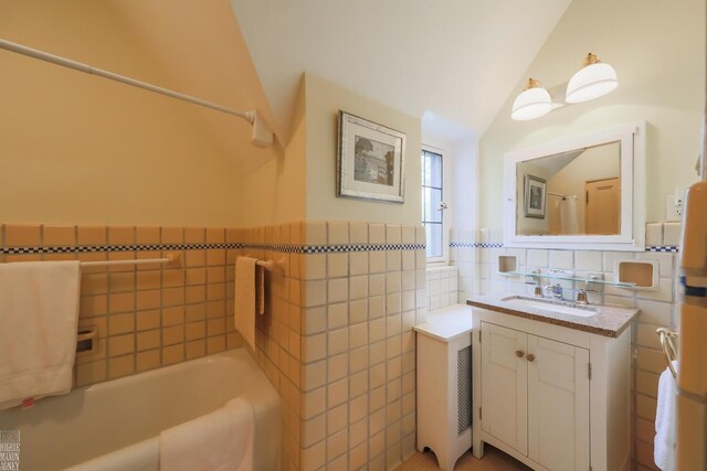 257 Ridge Rd, Grosse Pointe Farms, MI 48236 - bathroom featuring tile walls, vanity, a bathtub, vaulted ceiling, and a wainscoted wall