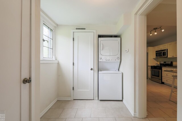 257 Ridge Rd, Grosse Pointe Farms, MI 48236 - laundry area with estacked washer and dryer, light tile patterned floors, and baseboards