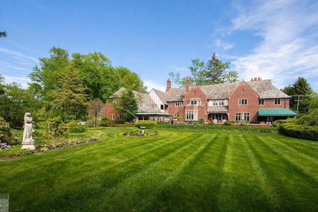 257 Ridge Rd, Grosse Pointe Farms, MI 48236 - rear view of property with a lawn, a standing seam roof, a chimney, and metal roof