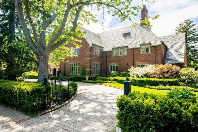 257 Ridge Rd, Grosse Pointe Farms, MI 48236 - tudor home with a high end roof, brick siding, a chimney, curved driveway, and a gate