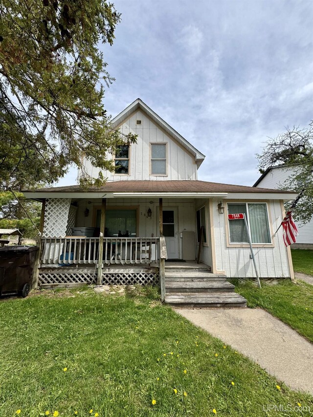 7848 Cole St, Rapid River, MI 49878 - view of front facade with covered porch, a front lawn, and board and batten siding