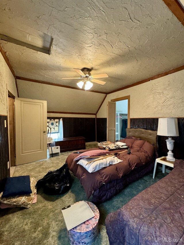 7848 Cole St, Rapid River, MI 49878 - bedroom with a textured wall, wood walls, carpet flooring, vaulted ceiling, and ceiling fan