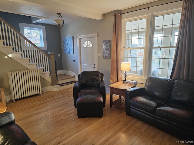 968 Baldwin Ave, Negaunee, MI 49866 - living area featuring radiator heating unit, light wood-style flooring, stairs, beamed ceiling, and baseboards
