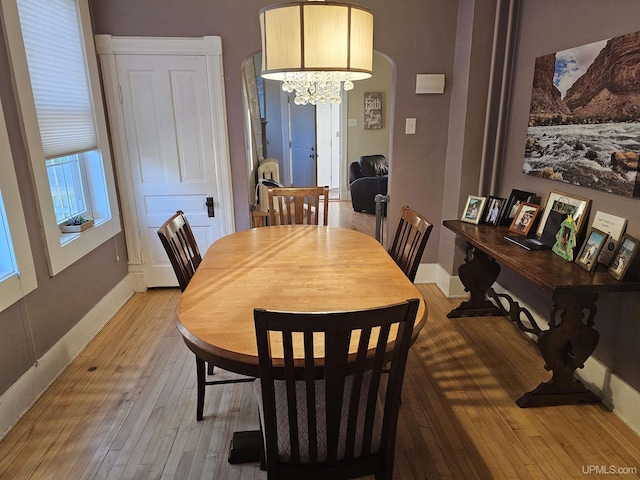 968 Baldwin Ave, Negaunee, MI 49866 - dining area featuring light wood-type flooring, a chandelier, baseboards, and arched walkways