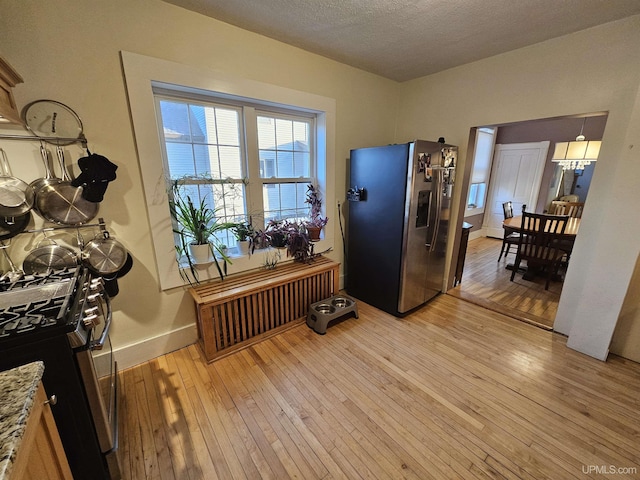 968 Baldwin Ave, Negaunee, MI 49866 - kitchen featuring appliances with stainless steel finishes, light wood-style floors, baseboards, a textured ceiling, and light stone countertops