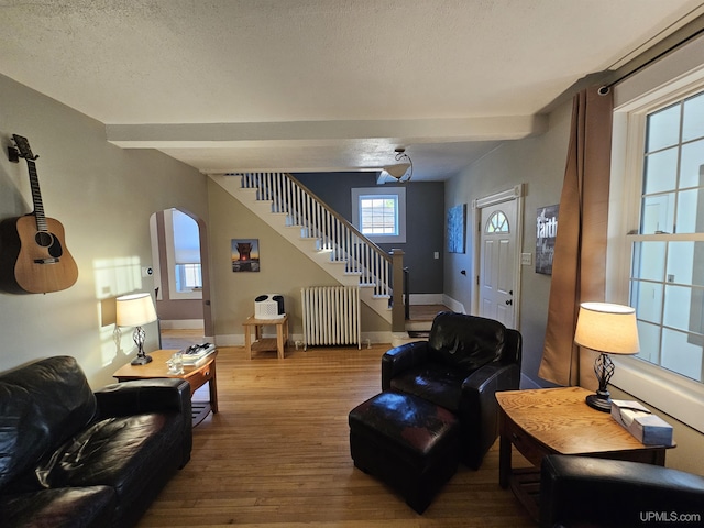 968 Baldwin Ave, Negaunee, MI 49866 - living room featuring radiator heating unit, stairs, wood finished floors, arched walkways, and baseboards