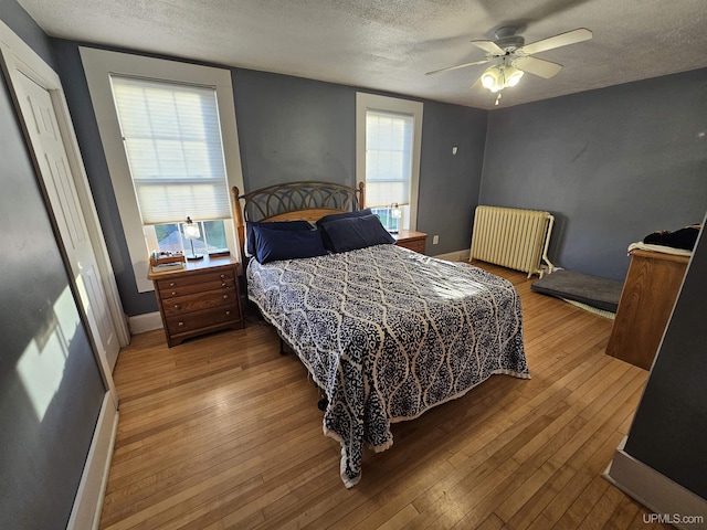 968 Baldwin Ave, Negaunee, MI 49866 - bedroom featuring radiator, a textured ceiling, hardwood / wood-style floors, baseboards, and a ceiling fan