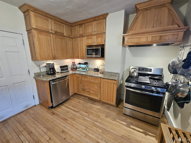968 Baldwin Ave, Negaunee, MI 49866 - kitchen with stainless steel appliances, custom exhaust hood, light wood-style floors, light stone countertops, and a textured ceiling