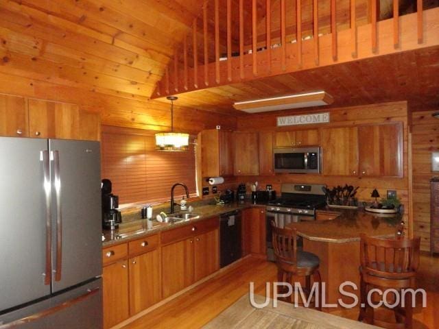 1417 Nestor St, Munising, MI 49862 - kitchen featuring stainless steel appliances, a sink, brown cabinetry, light wood-type flooring, and wood walls