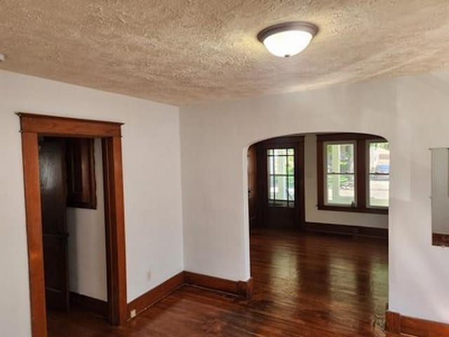 2515 Cooper St, Saginaw, MI 48602 - unfurnished room with a textured ceiling, arched walkways, baseboards, and wood finished floors