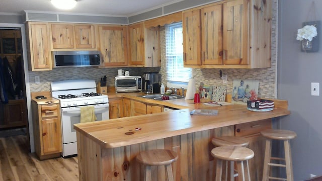 4158 Scott Ct, Gladwin, MI 48624 - kitchen with stainless steel microwave, white gas stove, ornamental molding, a sink, and a peninsula