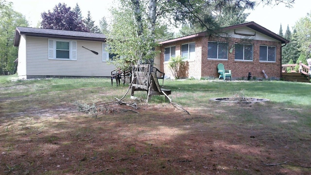4158 Scott Ct, Gladwin, MI 48624 - rear view of property with a fire pit, brick siding, and a lawn