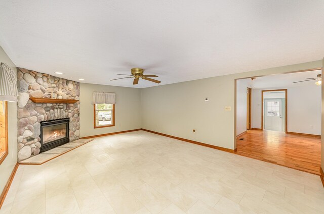 122 Shady Grove Ln, Roscommon, MI 48653 - unfurnished living room with ceiling fan, healthy amount of natural light, baseboards, and a stone fireplace