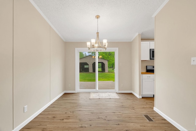 2100 Rowe Rd, Applegate, MI 48401 - unfurnished dining area with crown molding, a chandelier, light wood finished floors, a textured ceiling, and baseboards