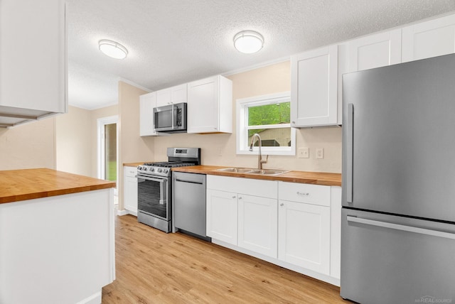 2100 Rowe Rd, Applegate, MI 48401 - kitchen with butcher block counters, appliances with stainless steel finishes, a sink, light wood-style flooring, and a textured ceiling