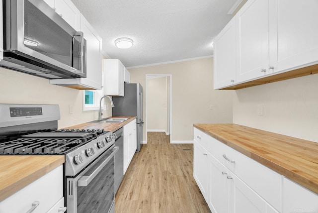 2100 Rowe Rd, Applegate, MI 48401 - kitchen with appliances with stainless steel finishes, wood counters, a sink, white cabinets, and ornamental molding