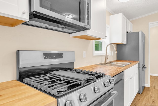 2100 Rowe Rd, Applegate, MI 48401 - kitchen featuring appliances with stainless steel finishes, wooden counters, white cabinets, a sink, and crown molding