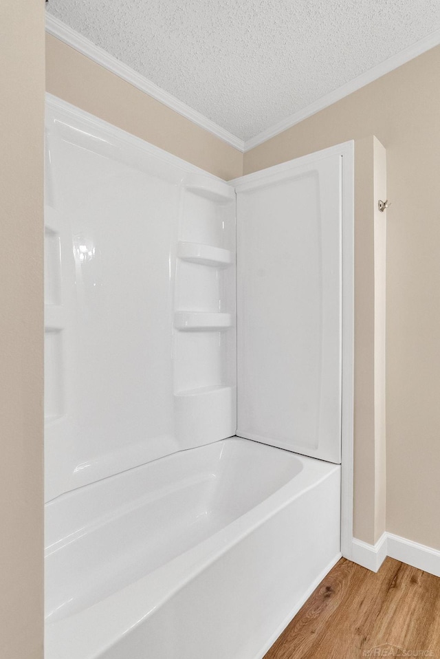 2100 Rowe Rd, Applegate, MI 48401 - bathroom featuring wood finished floors, crown molding, a textured ceiling, baseboards, and bathing tub / shower combination